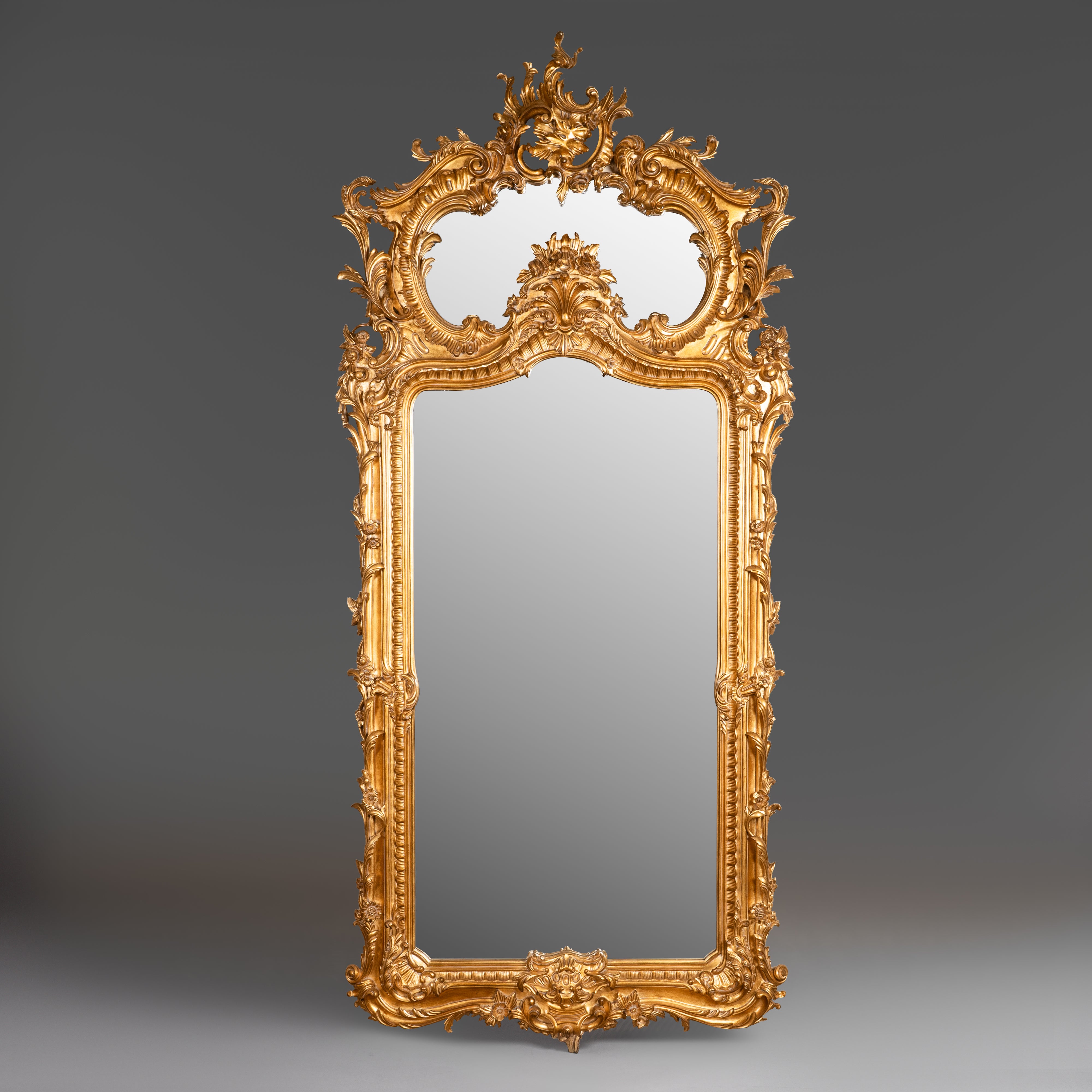 Exquisite Rococo-style giltwood mirror with  intricate carvings and an opulent  asymmetrical crest.