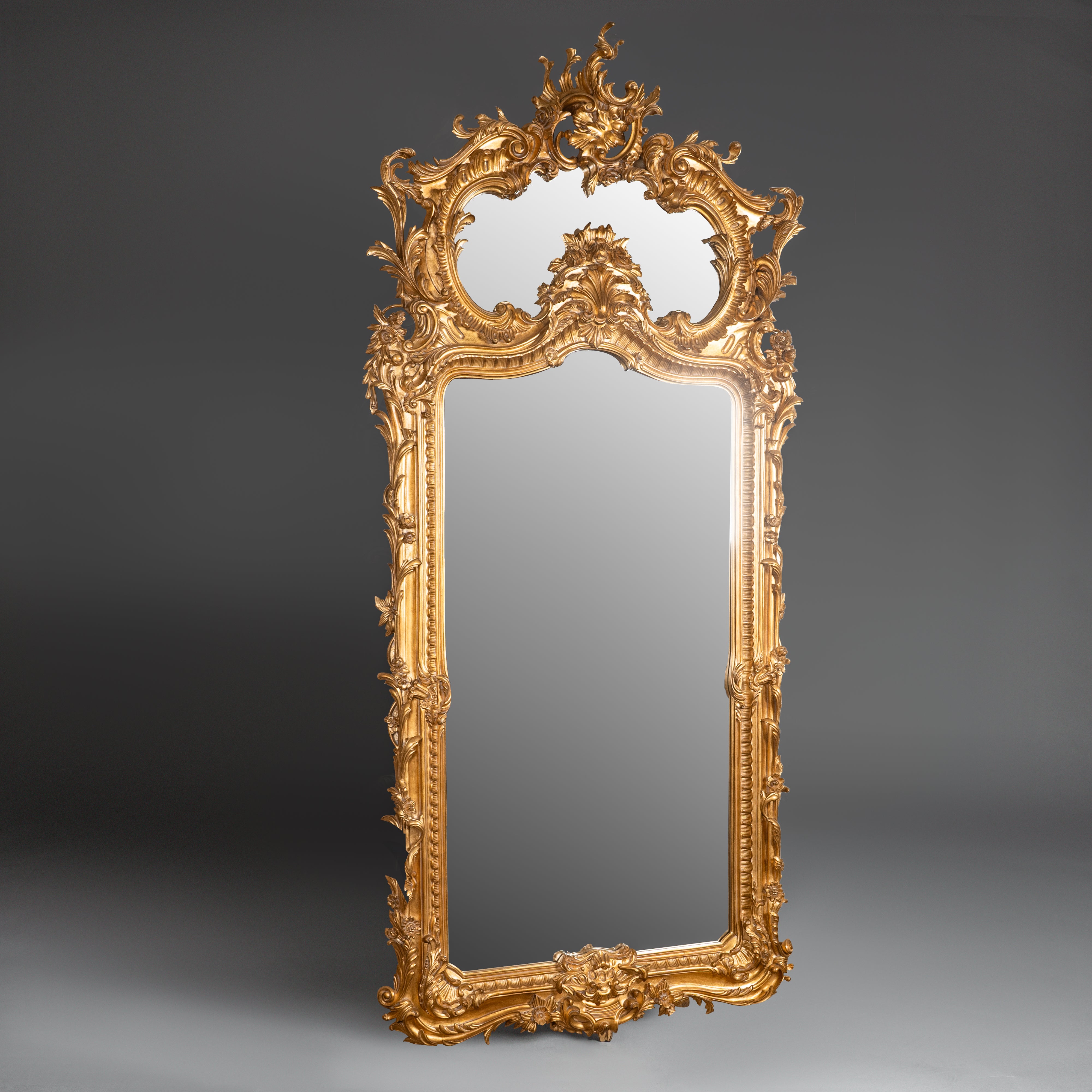 Exquisite Rococo-style giltwood mirror with  intricate carvings and an opulent  asymmetrical crest.