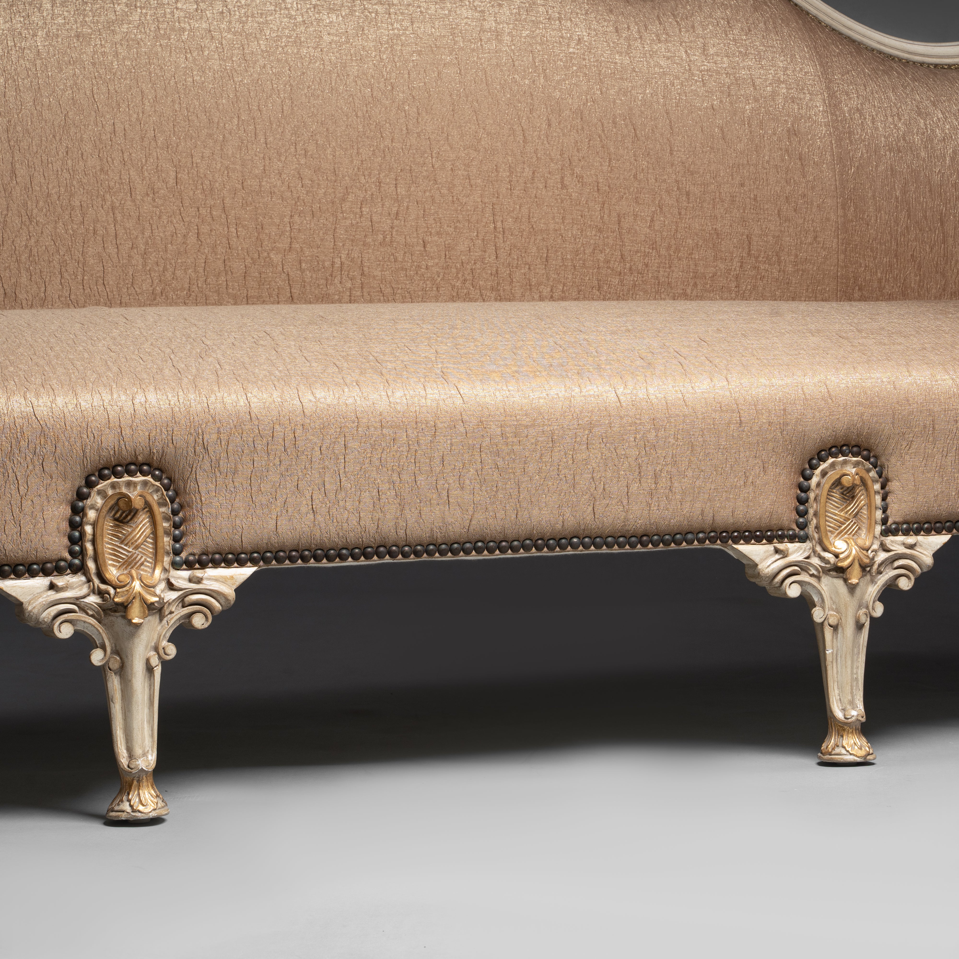 A regal Louis XV-style sofa with intricate  carvings and opulent upholstery.